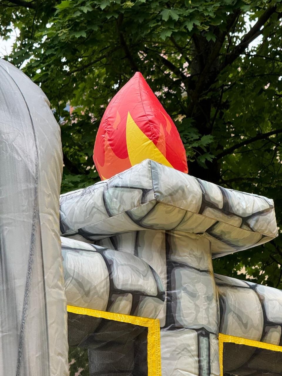T-Rex-Hüpfburg — Flammen-Deko am Steinturm